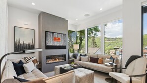 Una sala de estar moderna con chimenea, ventanas amplias y vistas al exterior.