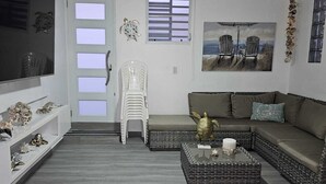 Una sala de estar con sofá, una mesa de centro, ventilador de techo y una ventana con persianas.