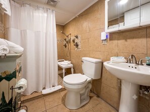 A bathroom with a toilet, bidet, sink, and shower curtain. - The Hartford | Coastal One Hundred (North Myrtle Beach)