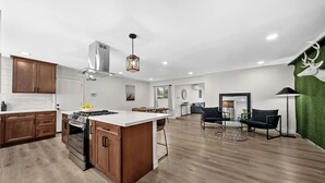 A modern kitchen with wooden cabinets, a central island, and a dining area with a round table and chairs. - San Diego Lake home 4 Bd/Bath with heated pool, hot tub and golf! (Lakeside)