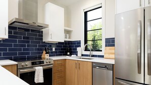 A modern kitchen with stainless steel appliances, wooden cabinets, and a blue-tiled backsplash.