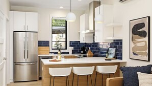 A modern kitchen with a central island, stainless steel appliances, and a bar seating area.