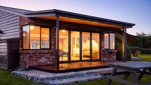 Een houten chalet met een overdekte veranda, grote ramen en een stenen rand.
