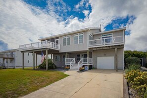 A two-story house with a balcony, a garage, and a flag. - The Real Thing II - 6 bedroom semi-oceanfront with pool (Virginia Beach)