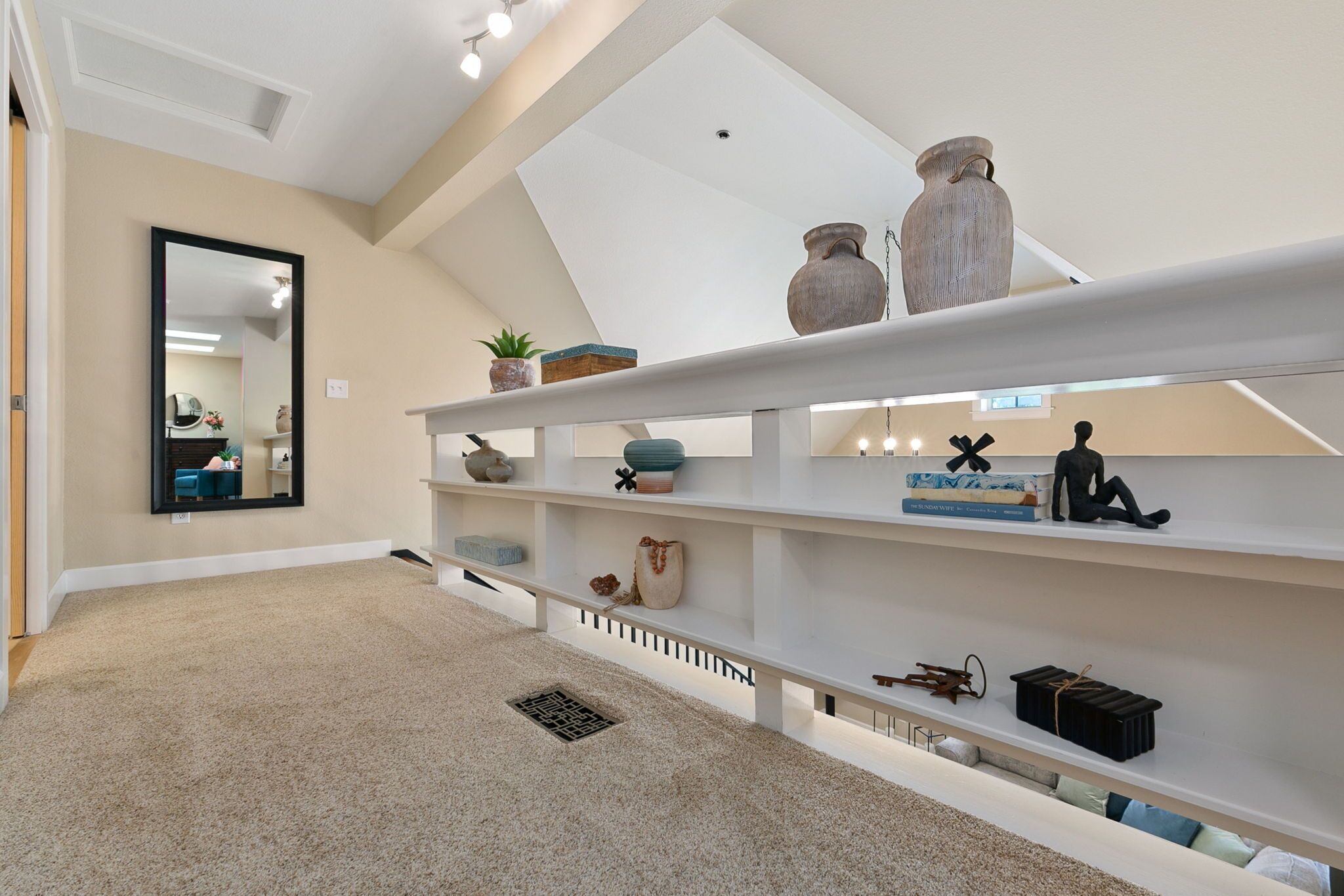 A spacious room with a high ceiling, a skylight, and a white shelving unit with various decorative items.