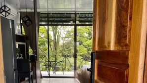 Une porte en bois qui donne sur une pièce offrant une vue sur la verdure environnante.