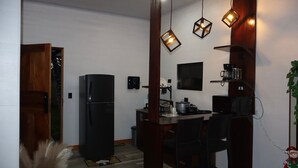 Une cuisine compacte comprenant un réfrigérateur, une table à manger avec des chaises et des luminaires suspendus.