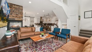 Een moderne woonkamer met een open haard, een bank, een salontafel en een blauwe fauteuil.
