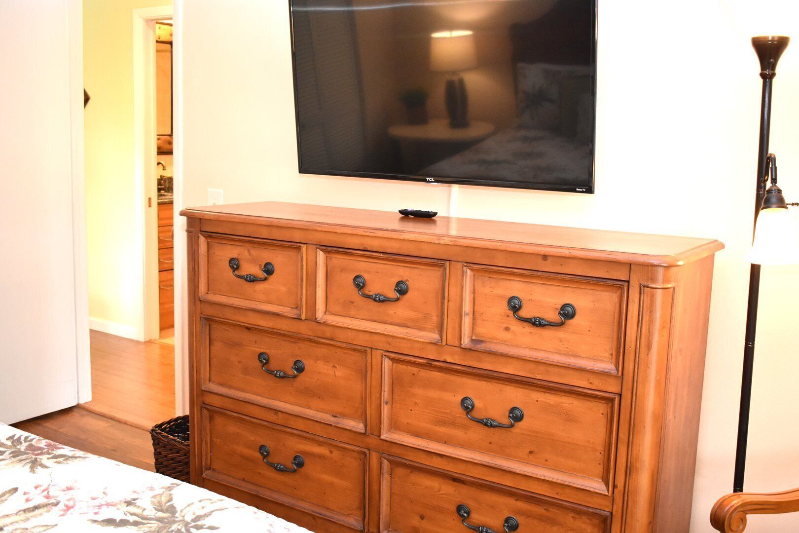 A wooden dresser with six drawers and a flat-screen TV mounted above it.