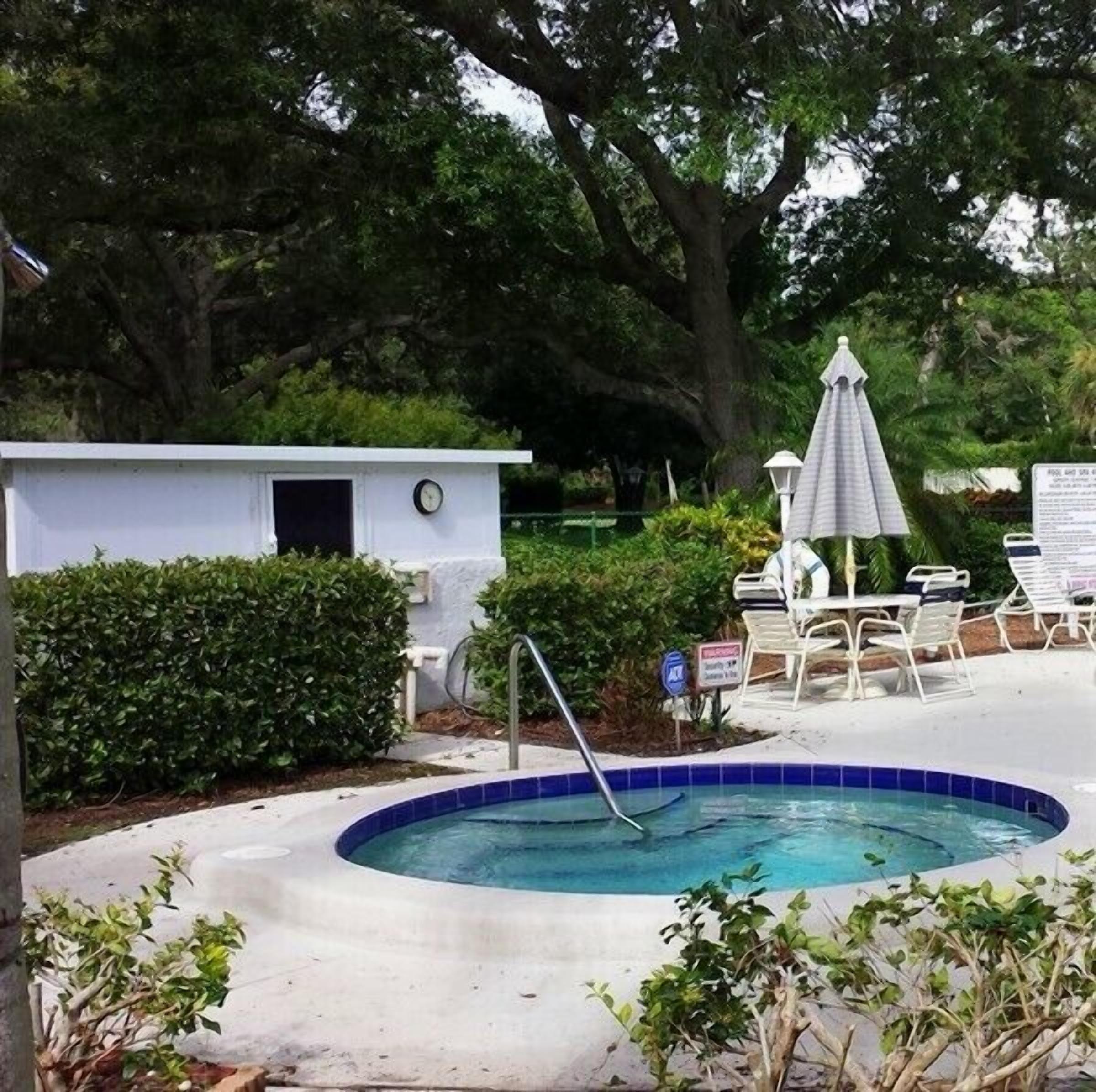 Uma pequena área de piscina com hidromassagem, espreguiçadeiras e um guarda-sol.