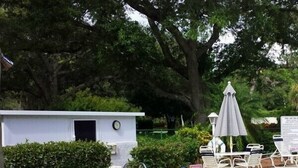 Uma pequena área de piscina com hidromassagem, espreguiçadeiras e um guarda-sol.