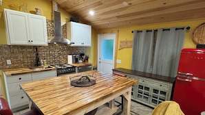 A compact kitchen with wooden cabinets, a central island, and a red refrigerator. - Soothing Carriage House with Hot Tub in charming Stratford (Stratford)