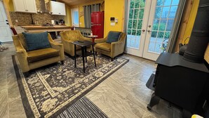 A cozy living room with a fireplace, a dining area, and a kitchen with wooden cabinets and a red refrigerator. - Soothing Carriage House with Hot Tub in charming Stratford (Stratford)