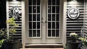 A house with a double door, two potted plants, a welcome sign, and a horse silhouette on the wall. - Soothing Carriage House with Hot Tub in charming Stratford (Stratford)