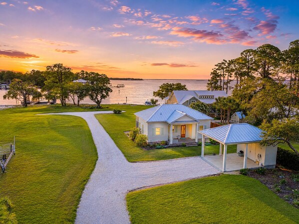 A coastal property with a paved driveway, a small house, and a gazebo.