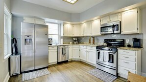 A modern kitchen with white cabinets, stainless steel appliances, and a granite countertop.