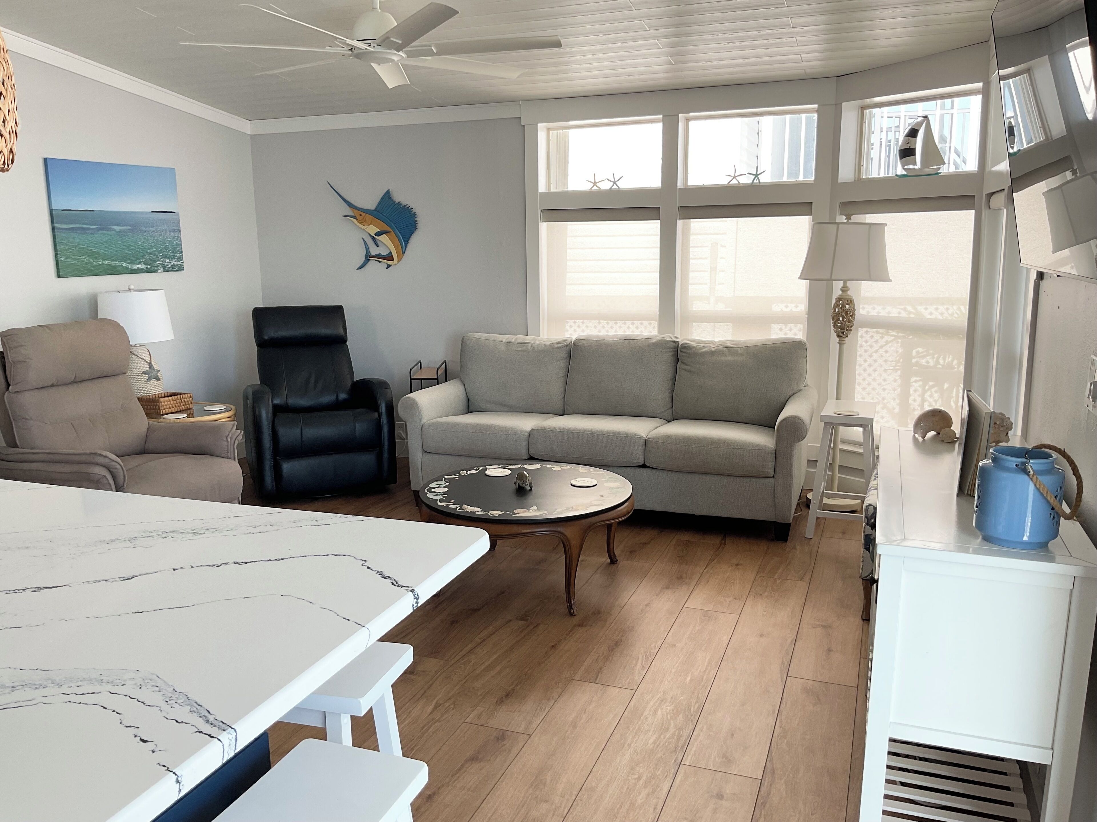Een woonkamer met een bank, fauteuils, een salontafel en een eettafel.