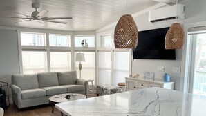 A modern living room with a sofa, a coffee table, and a kitchen island with a marble countertop. - Sea Cow Key Cottage - Venture Out Unit 585 (Cudjoe Key)