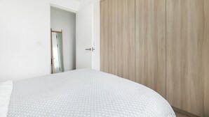 A bedroom with a bed, a wardrobe, and a door leading to another room. - Sun-Drenched Shoreditch 2BR Penthouse with Balcony (London)