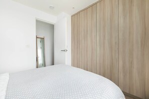 A bedroom with a bed, a wardrobe, and a door leading to another room.
