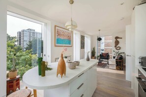 Una cocina moderna con una isla grande, un comedor con un sofá y vistas a la ciudad.