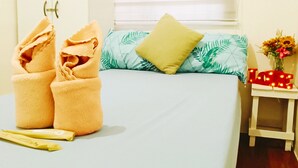 A hotel room with a bed, pillows, a nightstand, and a towel rack. - Amigas Transient House (Santo Tomas)