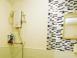 A bathroom with a shower, a wall-mounted mirror, and a tiled wall. - Amigas Transient House (Santo Tomas)