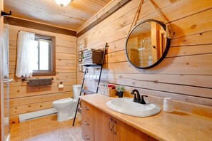 A wooden cabin bathroom with a toilet, sink, and a mirror.