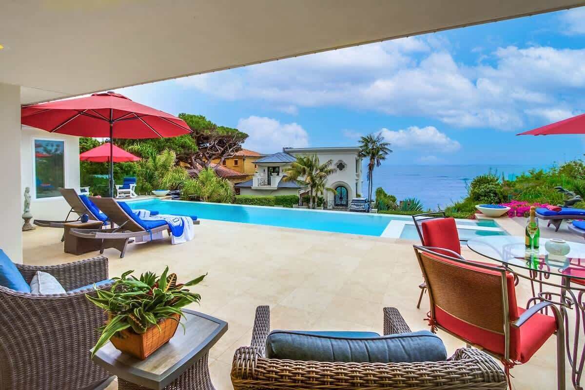 A poolside area with lounge chairs, umbrellas, and a view of the ocean.