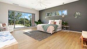 A modern bedroom with a large sliding glass door leading to a balcony, a bed with a view, and a ceiling fan. - Fred's at Fannie Bay (Fannie Bay)