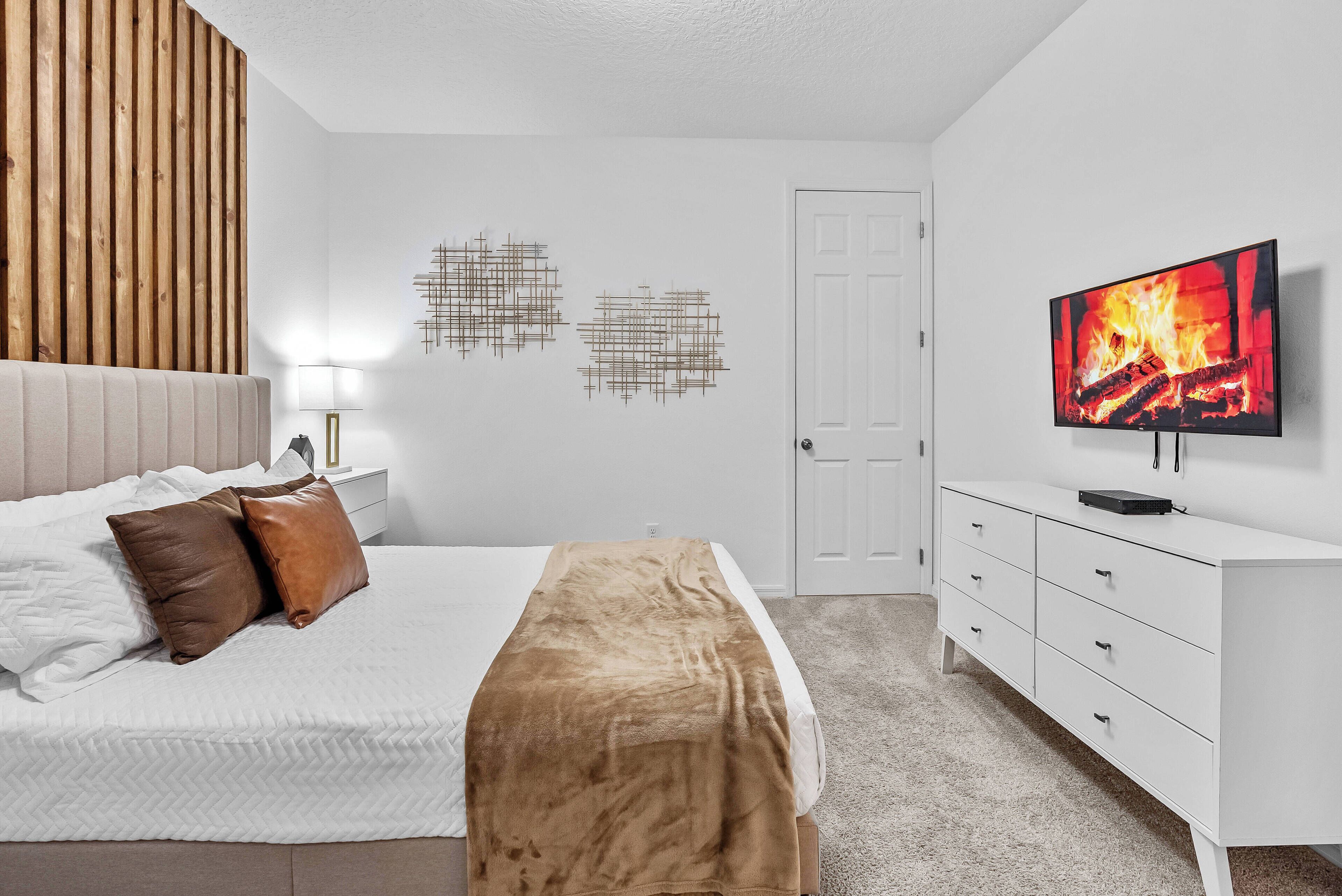 Une chambre à coucher moderne, avec un lit, une télévision et une commode.