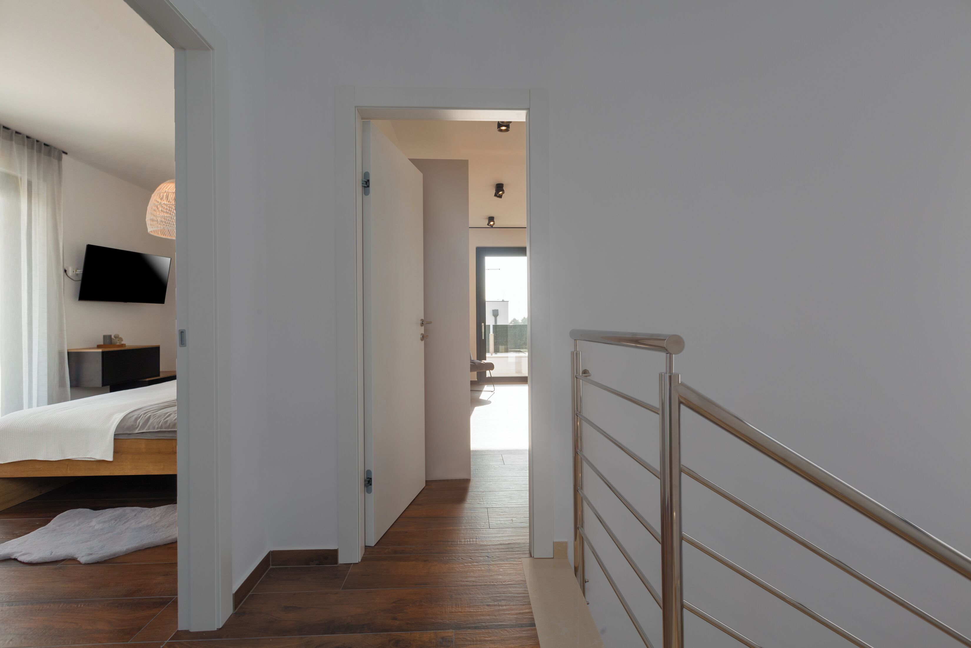Une chambre à coucher moderne avec un lit, un téléviseur à écran plat et un plancher en bois.