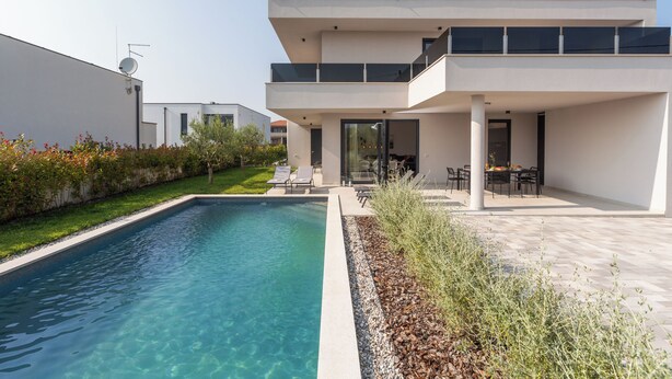 Une maison moderne à deux étages, dotée d’une piscine, d’un espace extérieur aménagé et d’un jardin bien entretenu.