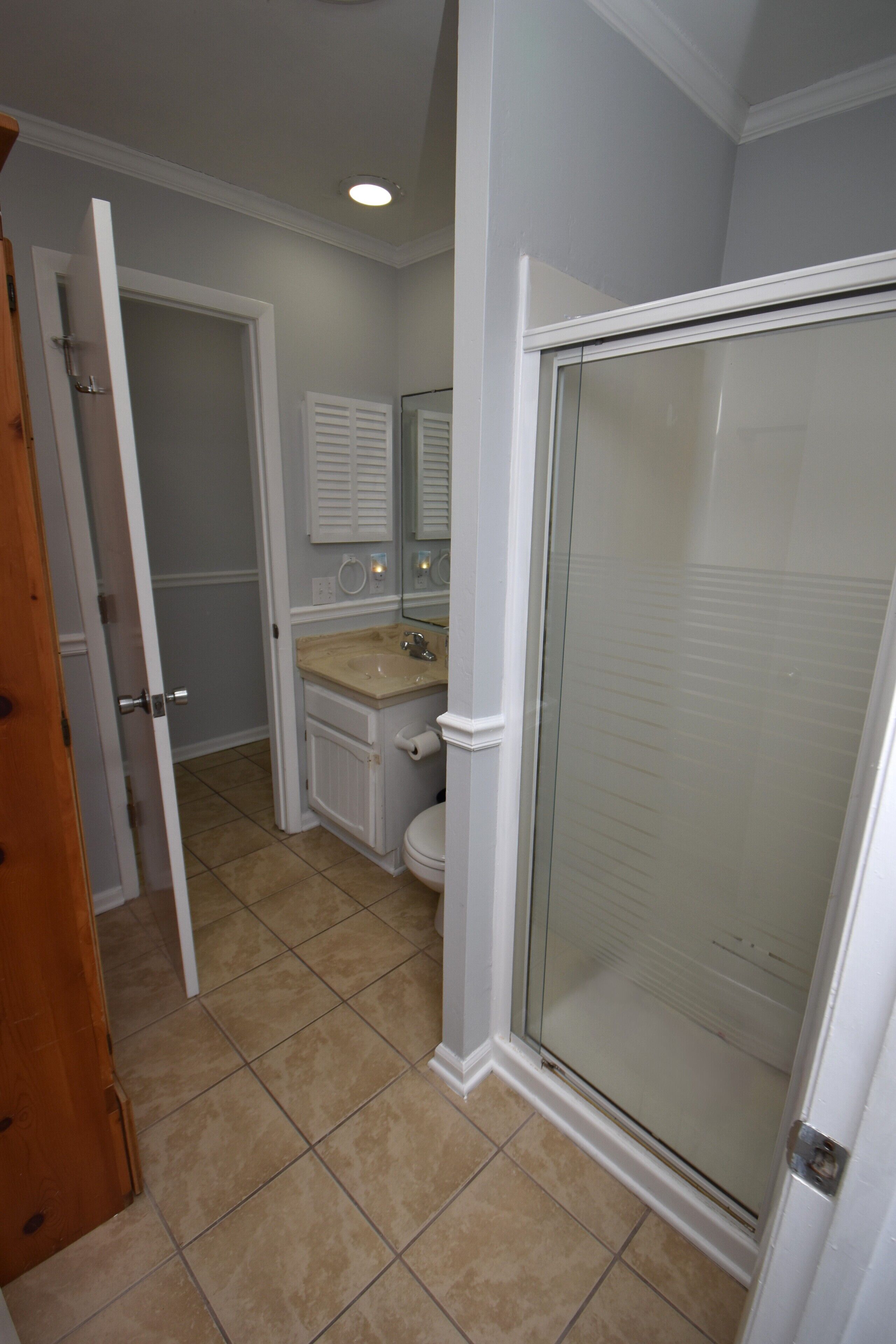 A bathroom with a glass shower door, a toilet, and a sink.