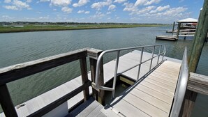 Un muelle de madera con barandilla de metal, que conduce a una embarcación amarrada.