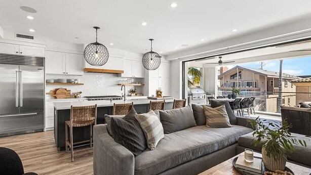 A modern kitchen with white cabinets, a stainless steel refrigerator, and a central island with seating. - 3BR Loft Ocean View Rooftop Hot Tub Parking (Newport Beach)