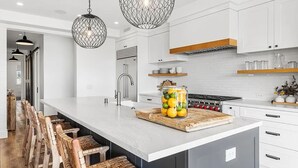 A modern kitchen with a large island, white cabinetry, and pendant lighting. - 3BR Loft Ocean View Rooftop Hot Tub Parking (Newport Beach)
