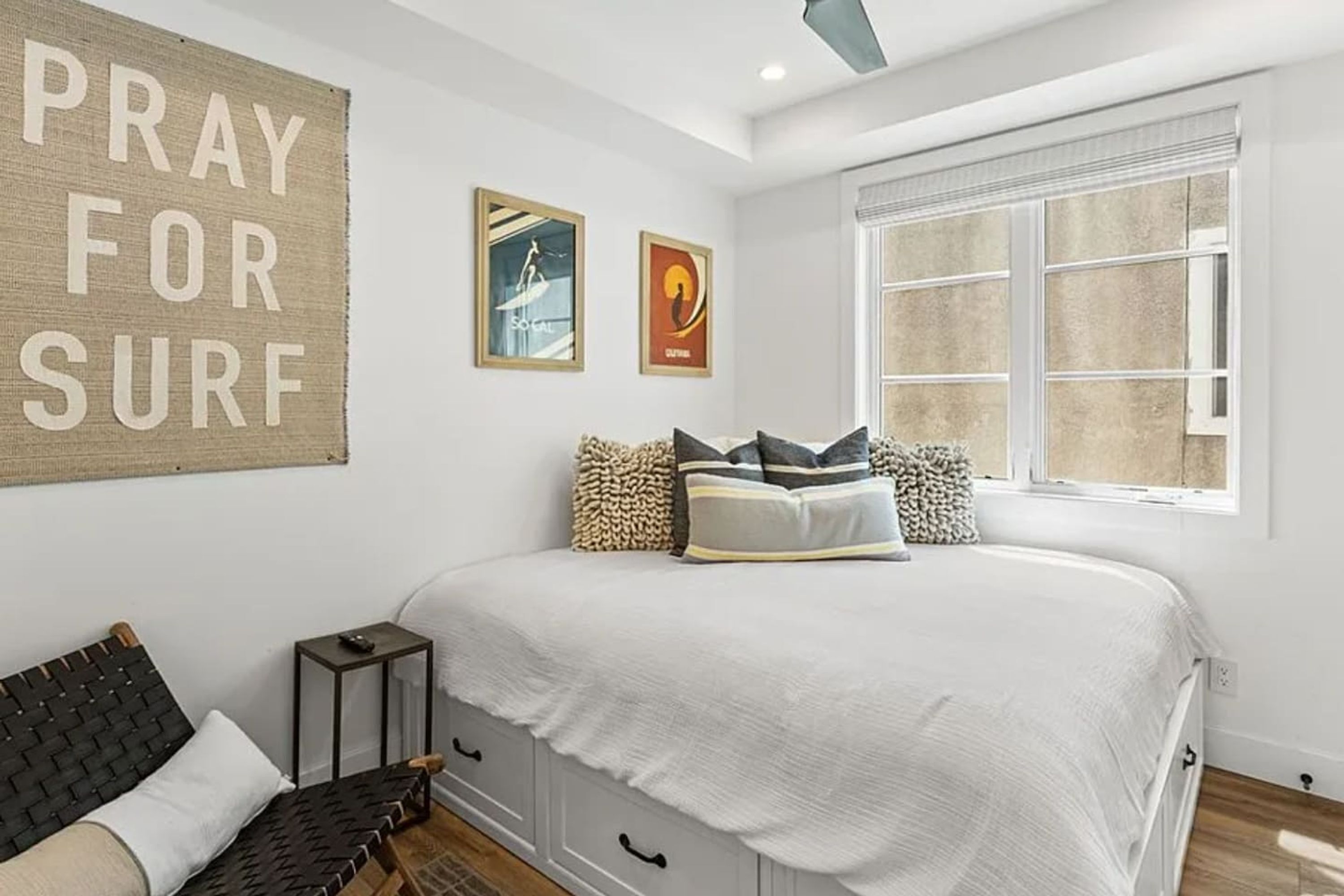 Un dormitorio con una cama, un banco, una mesita y una ventana.