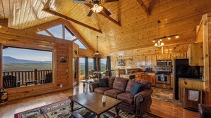 A spacious cabin with a large living area, wooden ceiling, and a kitchen with modern appliances. - Breathtaking Mountain Views • Resort Pool • Hot Tub • Sauna • Near Pigeon Forge (Sevierville)