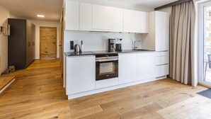 Una cocina moderna con armarios blancos, horno empotrado y cafetera.