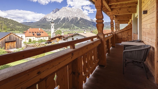 Un balcón de madera con vistas a una montaña e iglesia.