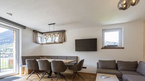 Una sala de estar moderna con comedor, un sofá y un televisor.