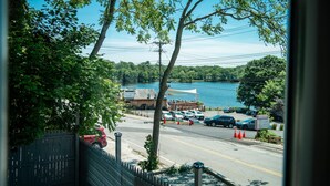 A view of a parking lot with cars, a building with a white roof, and a lake in the background. - Lakeview Getaway With Hot Tub (Billerica)