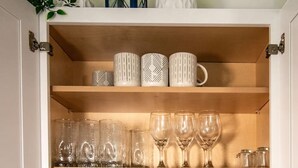 A kitchen cabinet with plates, glasses, and decorative mugs. - Lakeview Getaway With Hot Tub (Billerica)