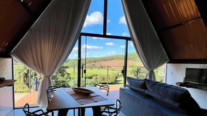 Ein Essbereich mit Tisch und Stühlen, einer Couch und Blick durch große Fenster.