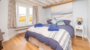 Une chambre à coucher avec un lit, une fenêtre, une table de chevet et un tableau au mur.