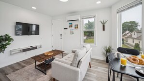 Ein modernes Wohnzimmer mit einer Couch, einem Couchtisch und einem an der Wand befestigten Fernseher.
