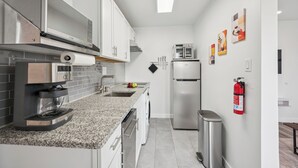 Eine moderne Küche mit Edelstahlgeräten, einer Arbeitsplatte aus Granit und einem eingebauten Backofen.