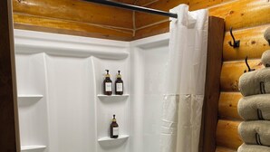 A wooden cabin bathroom with a shower, white shelves, and a toilet. - Bush Pilot Cabin-Modern Comfort in the Last Frontier (For families or casual travelers) (Tok)