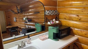 A wooden cabin bathroom with a sink, mirror, and a microwave on the counter. - Bush Pilot Cabin-Modern Comfort in the Last Frontier (For families or casual travelers) (Tok)